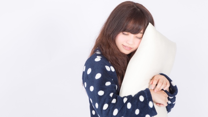 枕を抱いて眠る女性の画像
