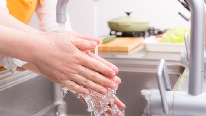 キッチンの流し台で手を洗う女性の画像